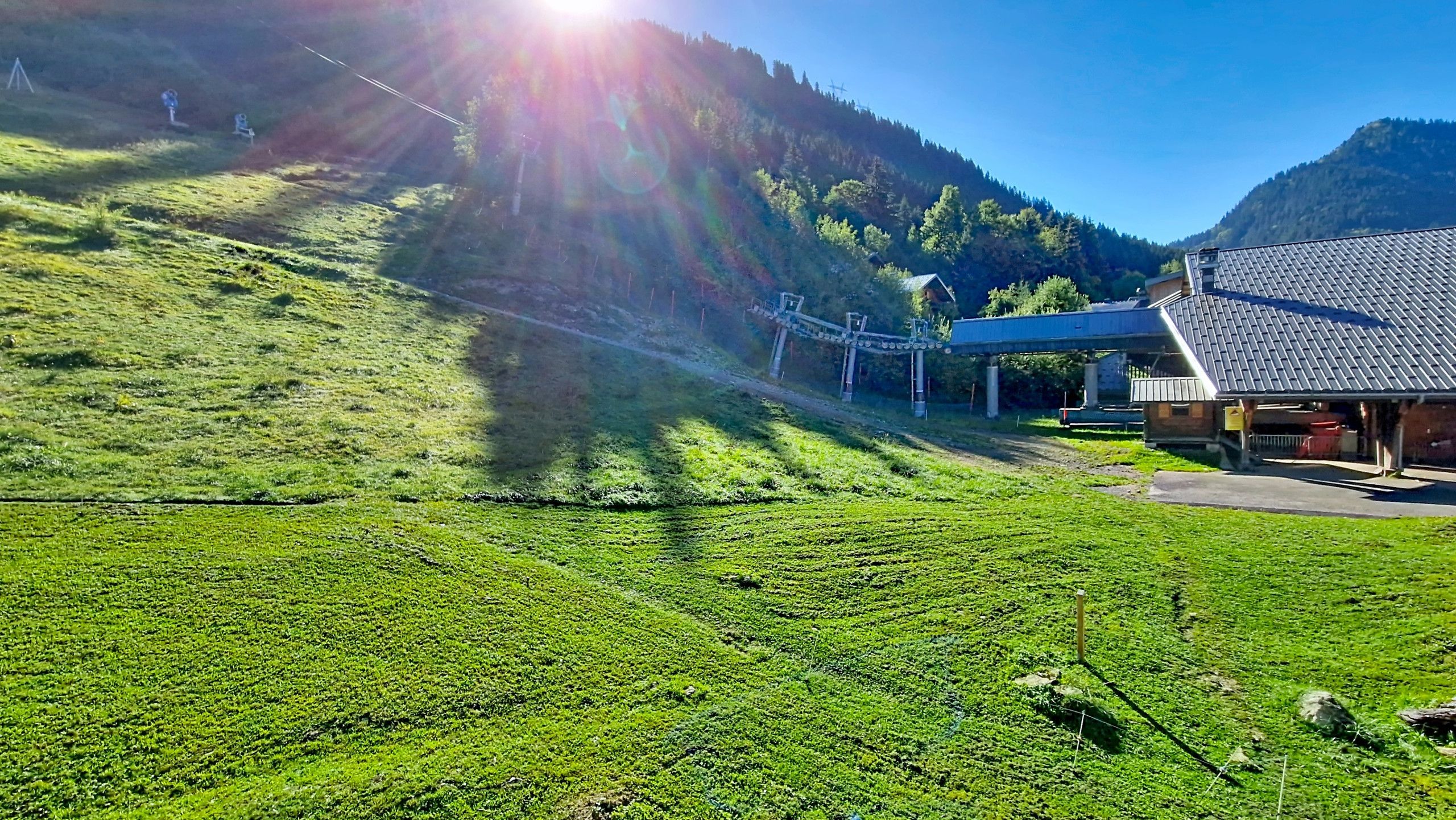 A green hillside with a building and a bridge.