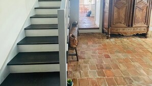 A staircase leading to a second floor, a wooden cabinet, and a tiled floor. - Grande Maison de Vacances et WE Près de Dinan (Trévron)