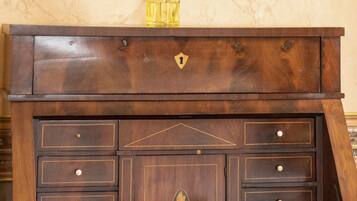 A wooden dresser with multiple drawers, a decorative emblem, and a tray with breakfast items including croissants, coffee cups, and orange juice glasses.