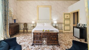Een luxueuze slaapkamer met een groot bed, een houten dressoir, een bureau en een stoel.