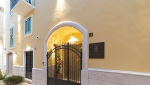 Een gebouw-ingang met een poortvormige boog, een plaquette waarop 'Luxury Rooms' staat en een bord met het nummer '3'.