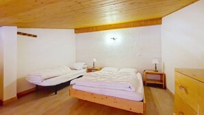 A bedroom with two beds, wooden flooring, a wooden ceiling, and a small wooden dresser. - Alpenlake AP120 VIEW & NATURE 5 pers. (Châtel)