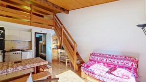 A cozy room with a wooden staircase, a dining area with a checkered tablecloth, and a colorful sofa. - Alpenlake AP120 VIEW & NATURE 5 pers. (Châtel)