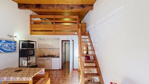 A compact living space with a kitchen, a dining area, and a staircase leading to a loft. - Alpenlake AP120 VIEW & NATURE 5 pers. (Châtel)