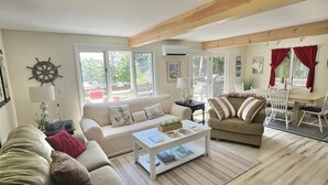 A spacious living room with a large sofa set, a coffee table, and a dining area with chairs and a table. - SEBAGO LAKE BEACH ACCESS (Sebago)