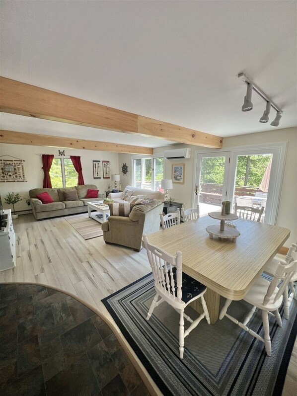 A spacious living area with a wooden floor, a dining table with chairs, a sofa, and a coffee table.