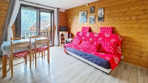 A wooden-paneled room with a bed, a table, chairs, and a television. - Corina CN11 QUIET & MOUNTAIN 4 Pers. (Châtel)