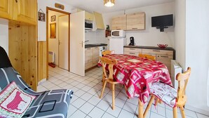 Une cuisine compacte comprenant une table à manger, des chaises et un four à micro-ondes.
