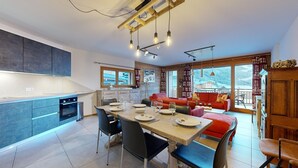 Una cocina moderna con comedor, un sofá rojo y vistas a un paisaje nevado.