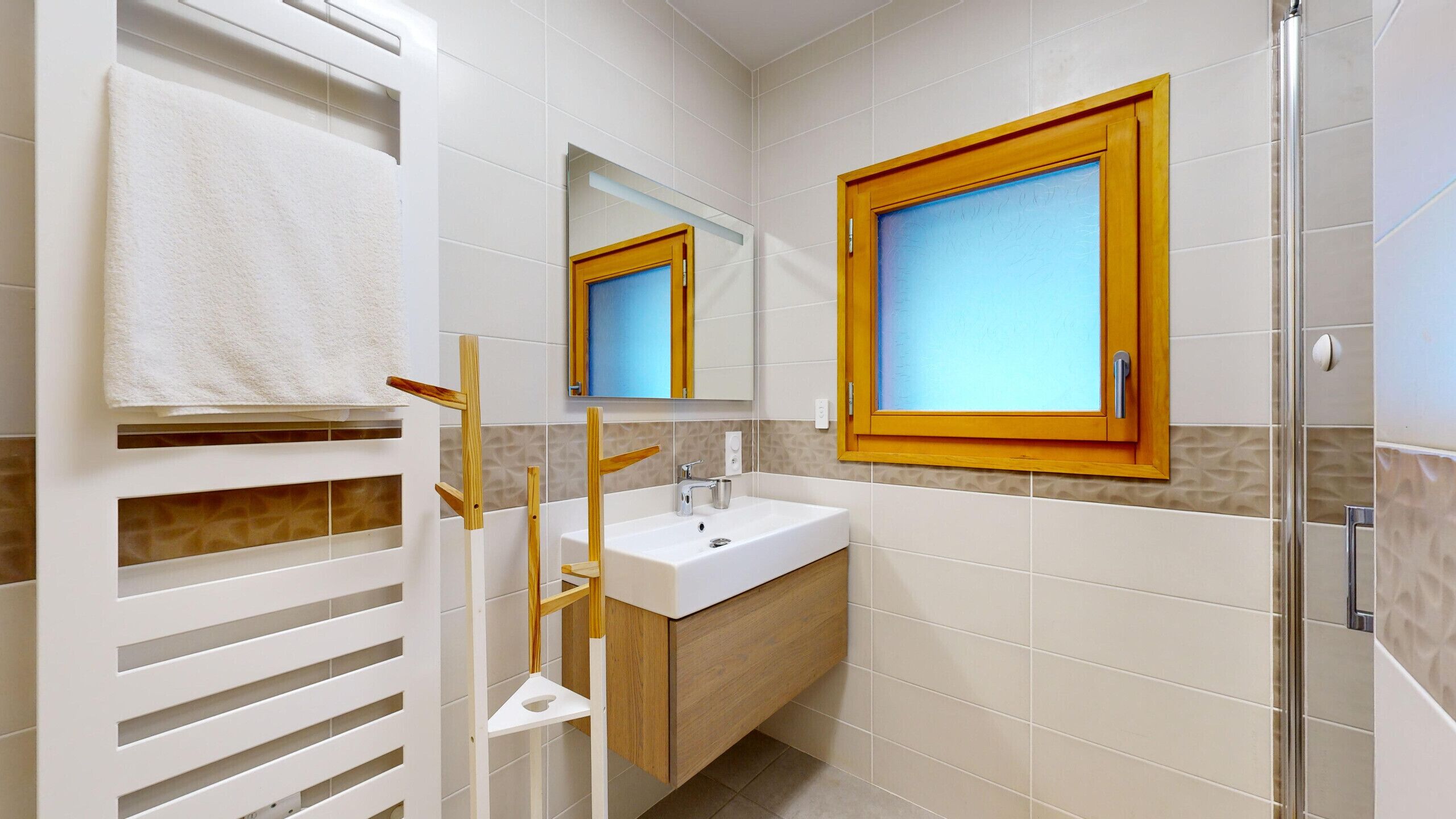 A bathroom with a white sink, a mirror, and a window.