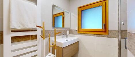 A bathroom with a white sink, a mirror, and a window.