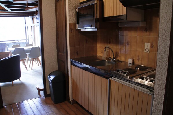 A compact kitchen with wooden cabinets, a stainless steel sink, and a microwave.