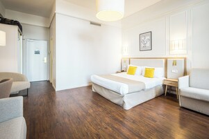 Una habitación de hotel con una cama grande, dos mesitas de noche, una silla y un armario.