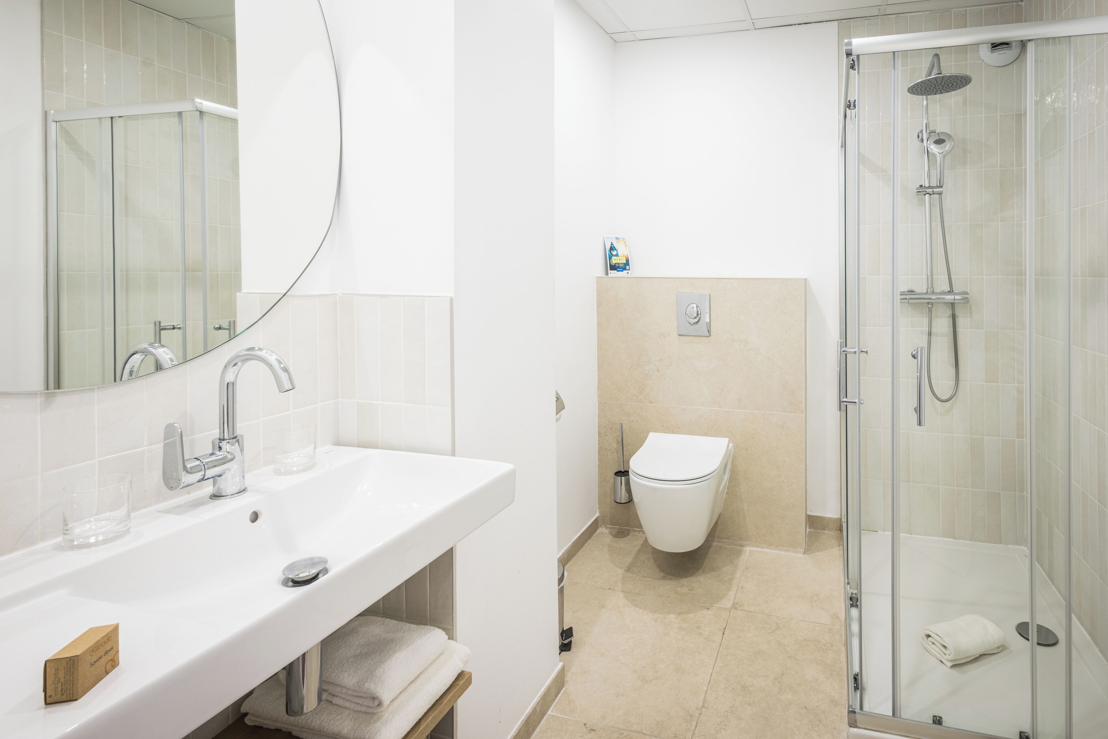 A bathroom with a glass-enclosed shower, a white sink, and a toilet.