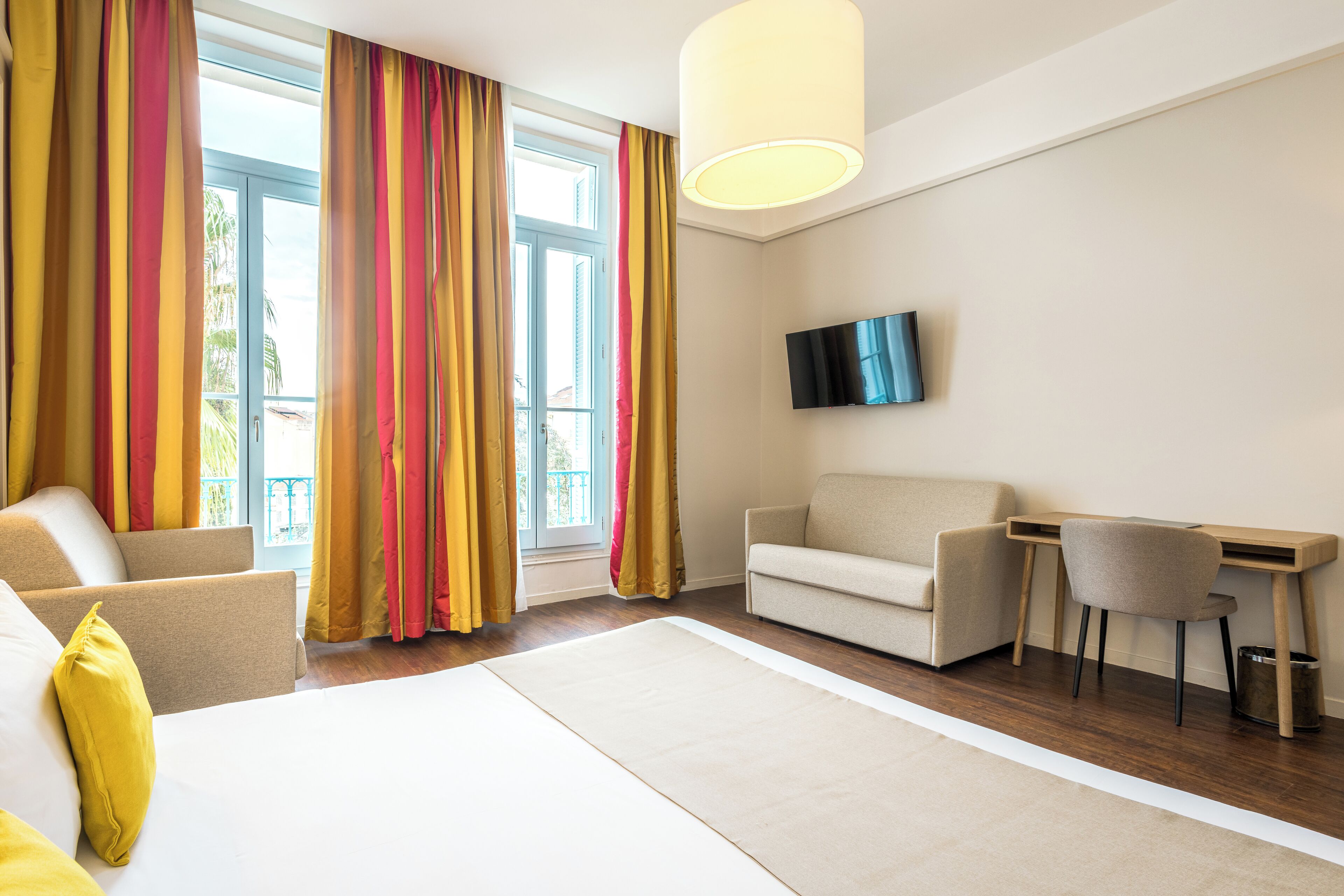 Une chambre d’hôtel avec un lit, un canapé, un bureau et une télévision.