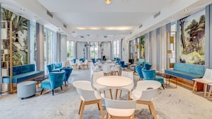 A spacious indoor area with multiple seating arrangements, including sofas and chairs, and a central round table. - L'Orangeraie Hotel by Miléade (Menton)