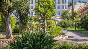 A hotel with a central courtyard, surrounded by lush greenery and trees. - L'Orangeraie Hotel by Miléade (Menton)