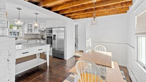 Una cocina moderna con armarios blancos, electrodomésticos de acero inoxidable y techo de madera.