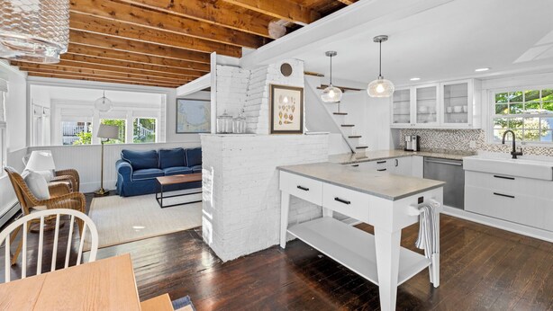 Una cocina moderna con armarios blancos, una isla de madera y un rincón de comedor con un sofá azul.