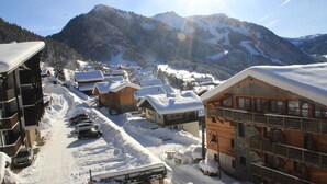 A snow-covered mountain village with wooden buildings and a ski slope.
