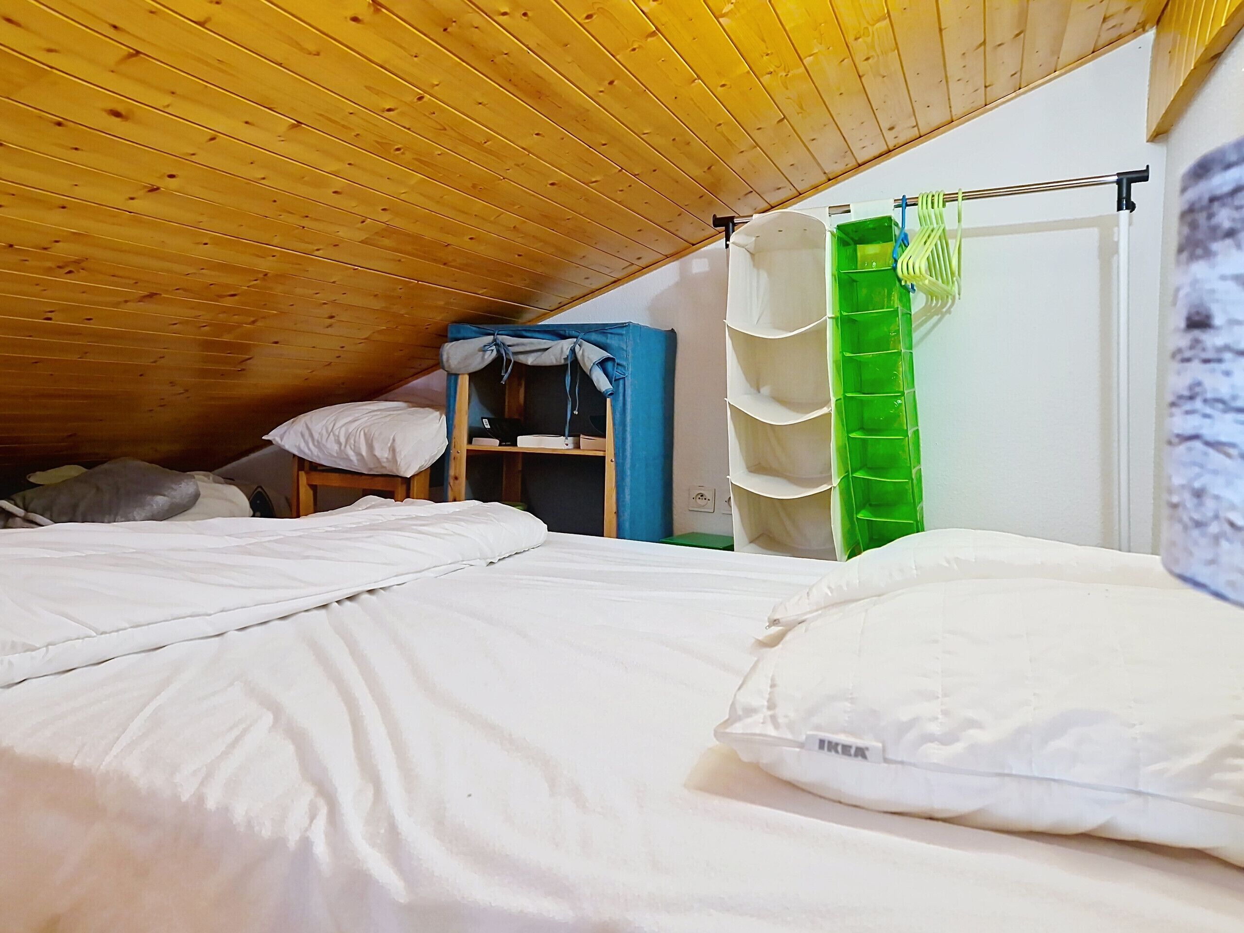 A dormitory room with bunk beds, a wardrobe, and a green storage unit.