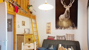 A cozy room with a loft bed, a dining table with a patterned tablecloth, and a large deer painting on the wall. - Forsythia FA18 FAMILY 1& NATURE 4 Pers. (Châtel)