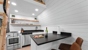 Una cocina moderna con una isla central, electrodomésticos de acero inoxidable y estantes de madera.