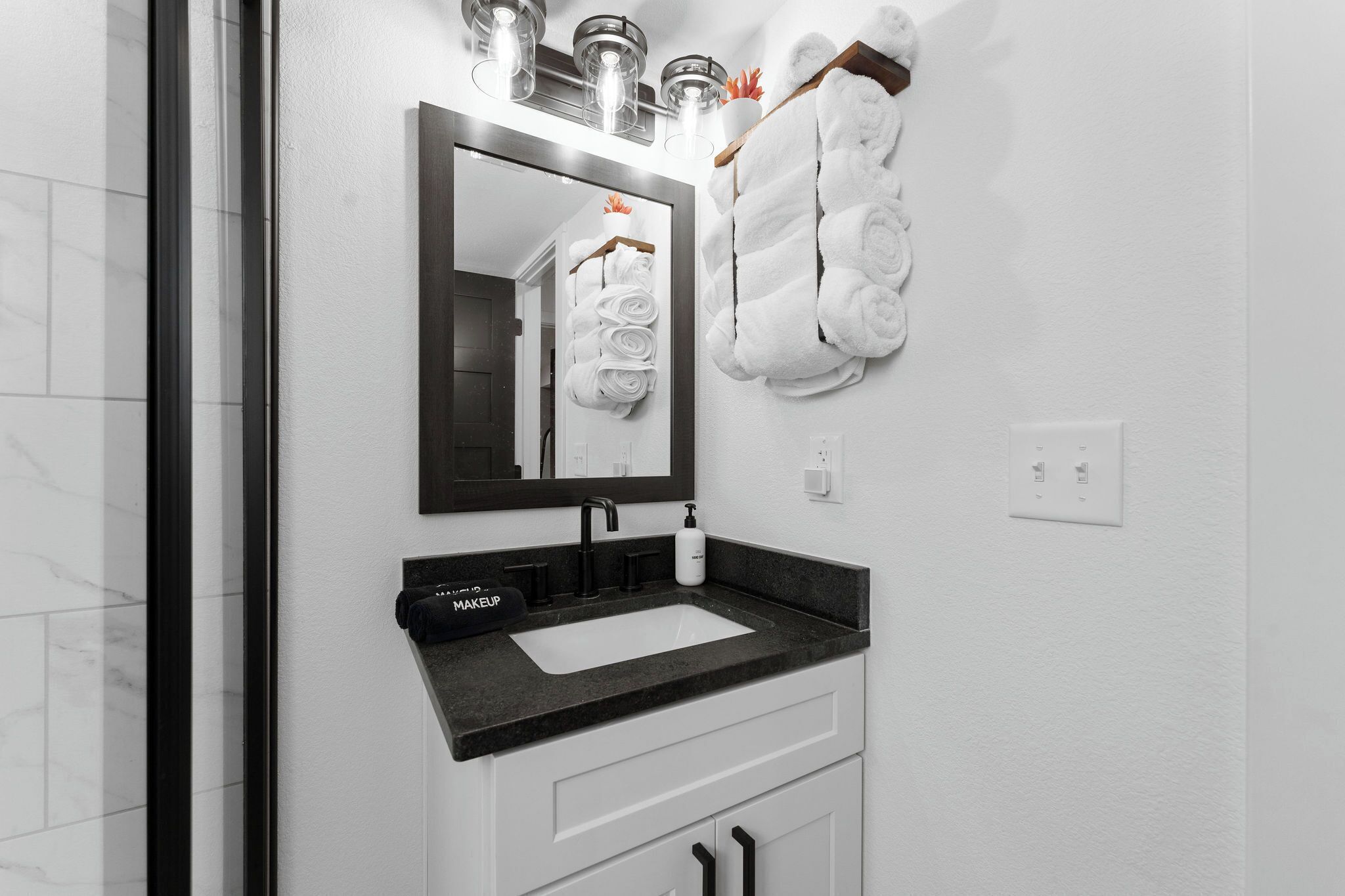A modern bathroom with a black countertop sink, a large mirror, and white towels hanging on a rack.