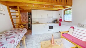A cozy cabin with a wooden loft bedroom, a kitchenette, and a dining area with a table and chairs. - Forsythia FA29 FAMILY 1& NATURE 8 Pers. (Châtel)