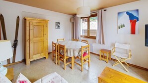 Un comedor con una mesa redonda, sillas de madera, un armario de madera y un cuadro en la pared.