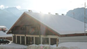 Un edificio con techo inclinado y balcón, rodeado de nieve y montañas.