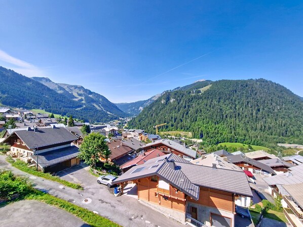 A mountainous village with traditional wooden houses, a clear sky, and a valley.