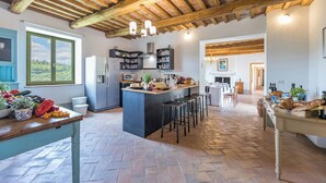 A spacious kitchen with a central island, wooden beams, and a large window. - Villa a Casa di Giovanni 12, Emma Villas (Acquapendente)