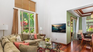 A living room with a sofa, coffee table, and a TV mounted on the wall. - Includes Mauna Lani Beach Club. Fairways at Mauna Lani 201 (Mauna Lani Resort)