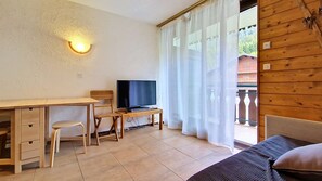 A room with a wooden desk, a television, a bed, and a window with curtains. - Moulin ML154 TELECABINE & MOUNTAIN 3 pers. (Châtel)