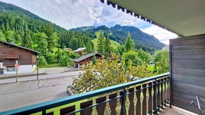 Ein Balkon mit Blick auf eine Berglandschaft, eine Straße und ein Gebäude mit einem geneigten Dach.