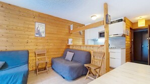 Ein kleines Zimmer mit einer Couch, einem Tisch und einer Küchenzeile.