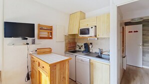 Une cuisine compacte avec des meubles en bois, un four à micro-ondes, un lave-vaisselle et un petit plan de travail.