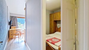 A bedroom with a wooden bed, a desk, and a chair in a hallway. - SOLARIUM SR19 SUNNY & VIEW 2 Pers. (Châtel)