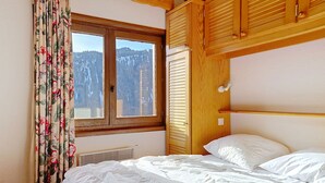 A bedroom with a bed, a window with curtains, a wooden headboard, and a view of mountains. - SORBIERS SS11 VIEW & QUIET 6 Pers. (Châtel)