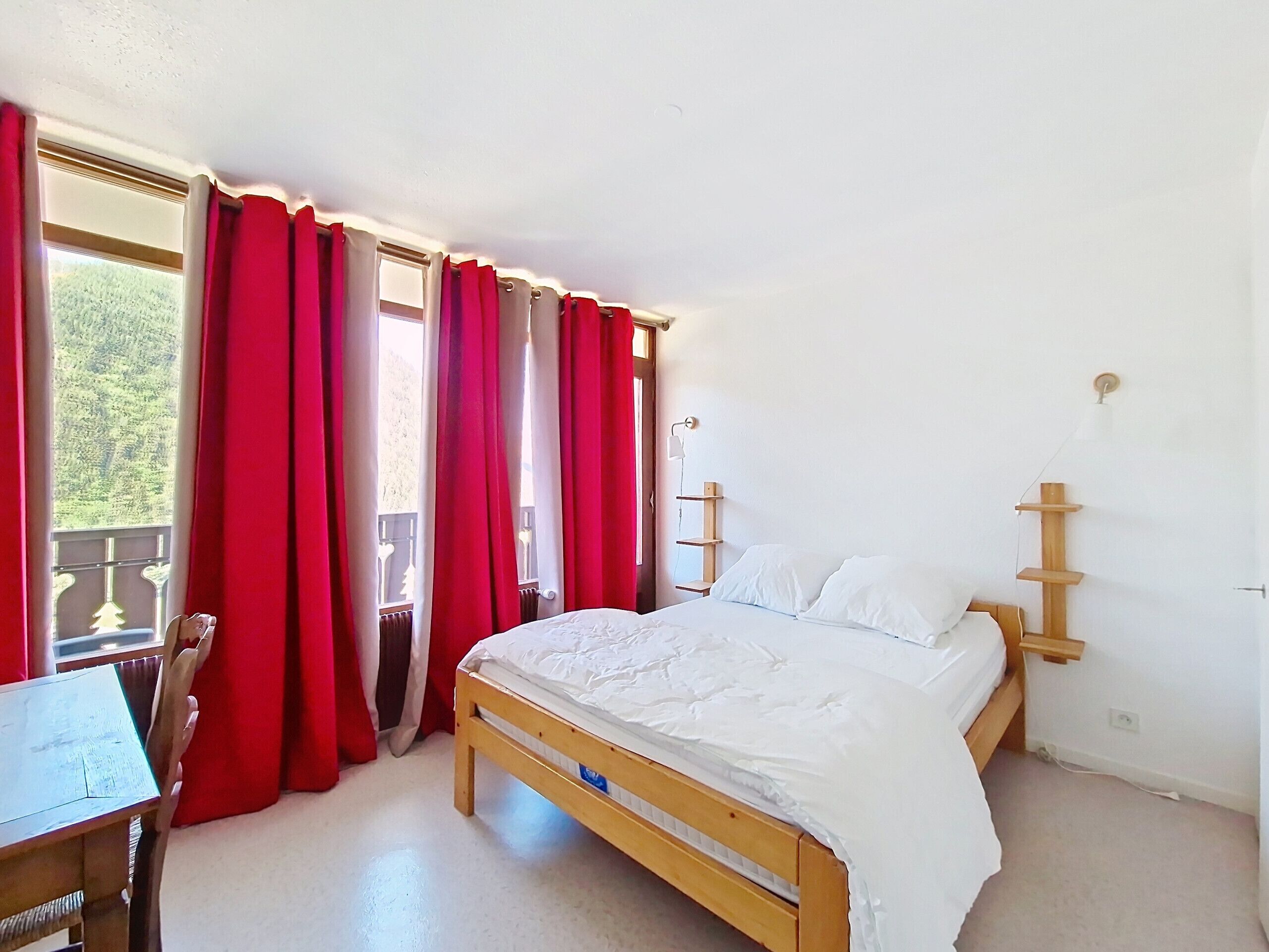 Quarto com uma cama de madeira, uma escrivaninha e uma cadeira.