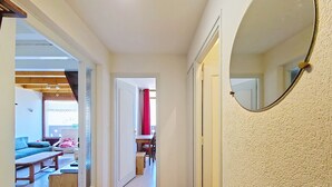 A hallway with a wooden floor, a dining area with a table and chairs, and a red curtain. - Castel des Neiges CSA4 CENTRE & VIEW  6 Pers. (Châtel)
