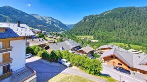 A residential area with houses, a clear blue sky, and a mountain backdrop. - Castel des Neiges CSA4 CENTRE & VIEW  6 Pers. (Châtel)