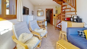 Una sala de estar acogedora con una escalera de madera, un comedor y una cocina.