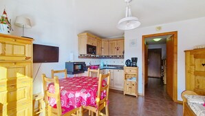 A compact kitchen with wooden cabinets, a microwave, and a coffee maker. There is a dining table with chairs and a red tablecloth. - Barbessine BBB18 SUN & CHAIR LIFT 4 pers. (Châtel)