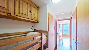 A room with bunk beds, wooden cabinets, a ceiling light, and a view of a balcony through an open door. - Barbessine BBB18 SUN & CHAIR LIFT 4 pers. (Châtel)