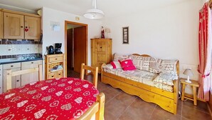 A cozy room with a bed, a sofa, a small table, and a kitchen area. - Barbessine BBB18 SUN & CHAIR LIFT 4 pers. (Châtel)