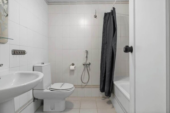 A bathroom with a toilet, sink, shower, and bathtub.