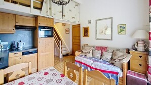 A cozy, compact living space with a kitchenette, a dining area, and a staircase leading to an upper level. - Chalet Madeline MD25 SUN & VIEW 6 pers. (Châtel)
