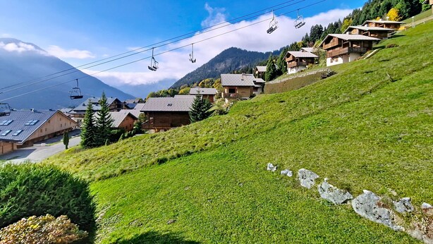 A hillside village with traditional wooden houses, a ski lift, and a mountain in the background. - Chalet Madeline MD25 SUN & VIEW 6 pers. (Châtel)